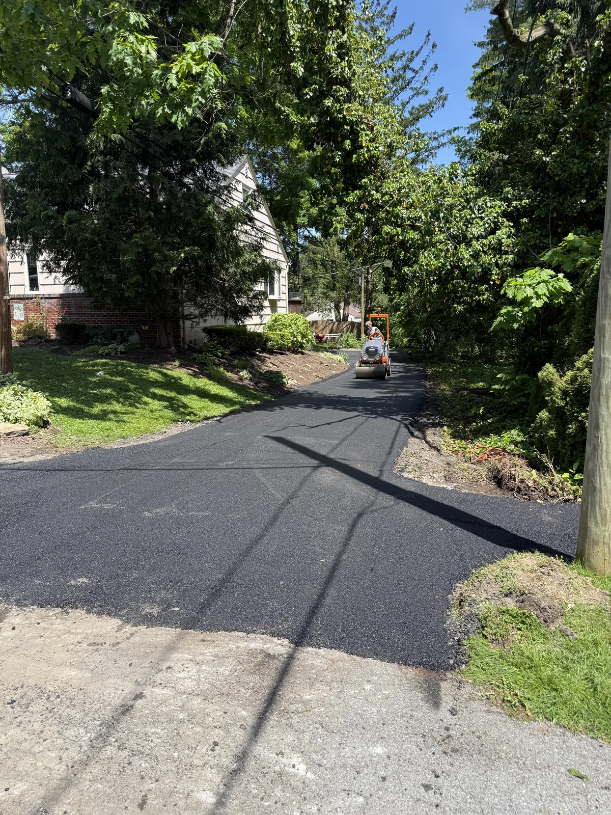 Finished asphalt driveway and entrance beside landscaped grounds