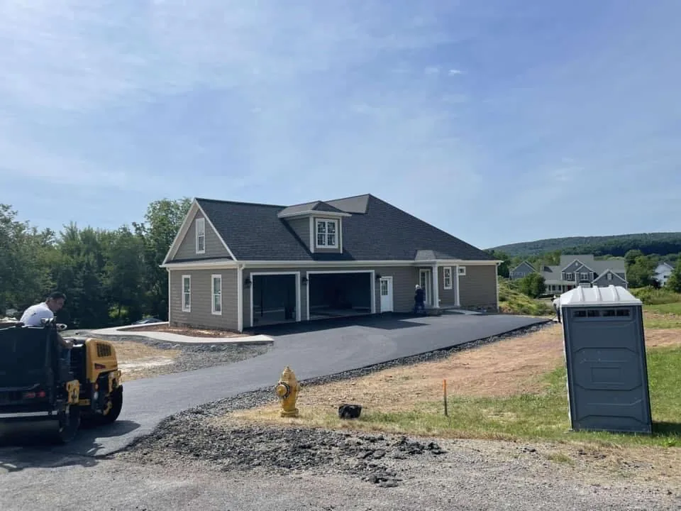 Asphalt driveway paving and compaction beside a newly built garage