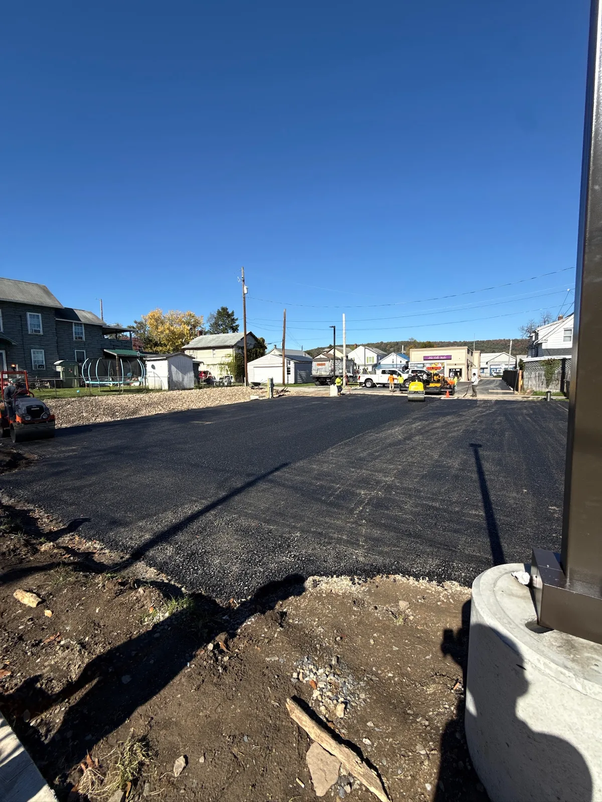 Parking-area asphalt work, with the paved surface extending toward equipment.