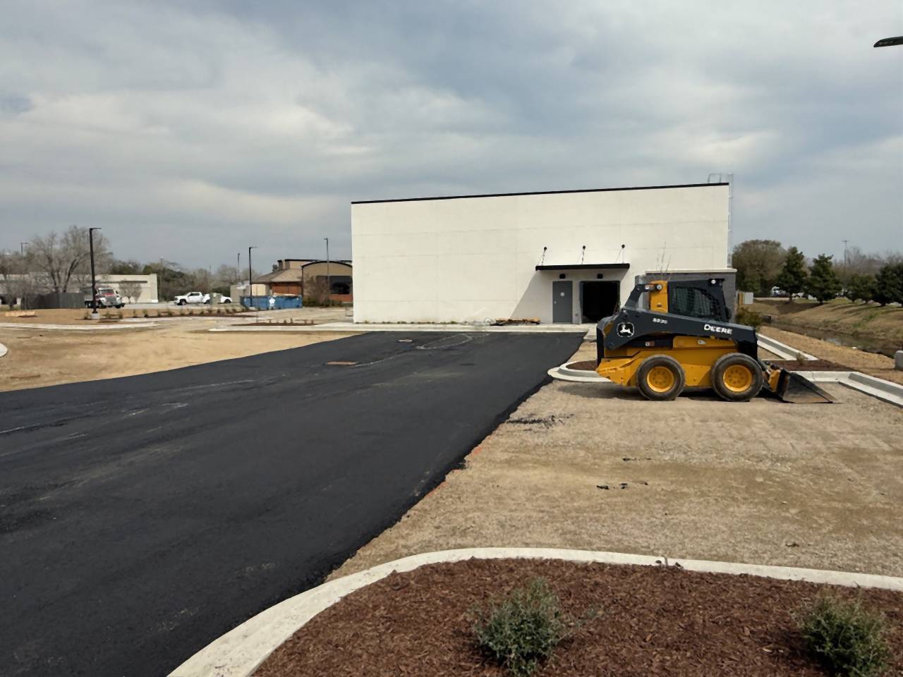 Binder course placed along a concrete-curbed island at a commercial site.