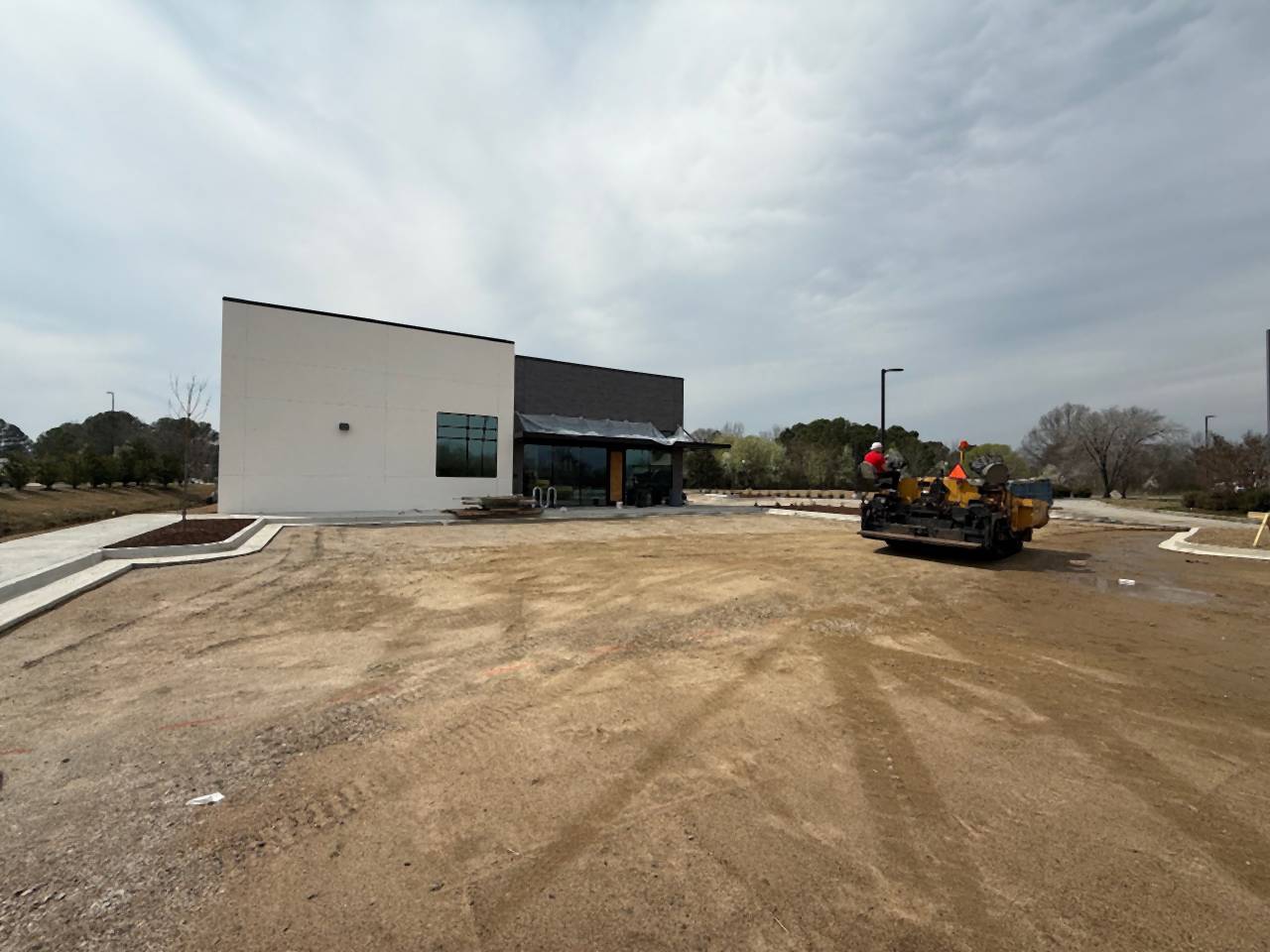 Graded site with equipment working in front of a new commercial building, before paving.
