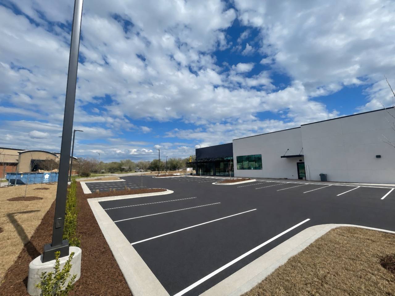Finished, striped commercial parking lot with curbed islands and a light pole.