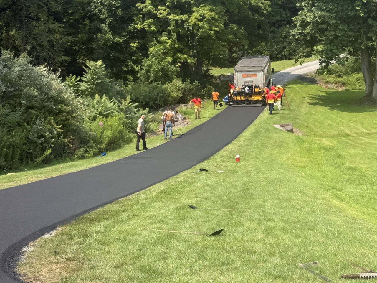 Long curving private road freshly paved through trees.
